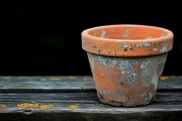 Naklejka premium Rustic clay pot with weathered texture on a wooden surface, emphasizing natural simplicity and history