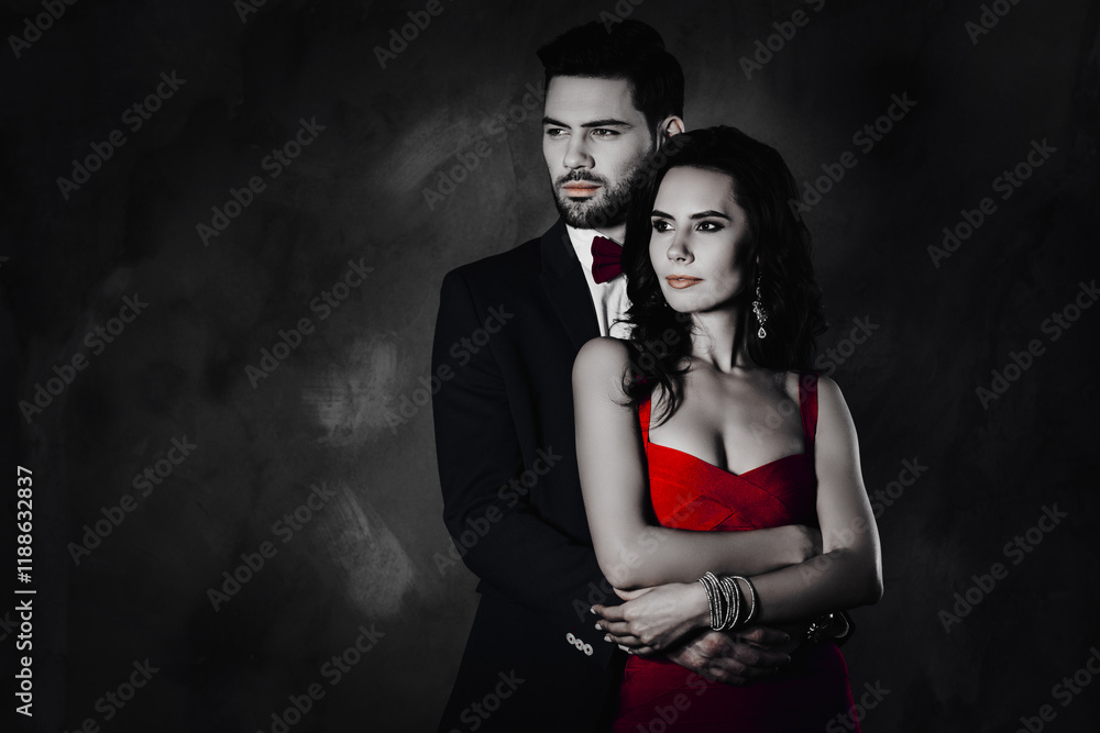 Poster portrait of lovely romantic couple embracing looking to the side, man with stubble in tuxedo with bo