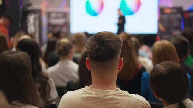 Creative minds gather for self-improvement talk, blurred presenter on stage. Event centered on personal growth in creative fields. Suitable for self-development, creative workshops content