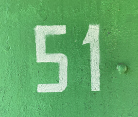 Number 51. White number fifty-one on textured green background with old cracked paint