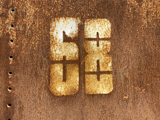 White number 68 on textured rusty background. Sixty-eight