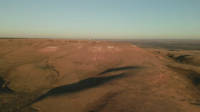 Vast dry landscape with communication tower on hilltop under clear sky