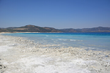 a coast with a medicinal clay and a blue lake and mountains 