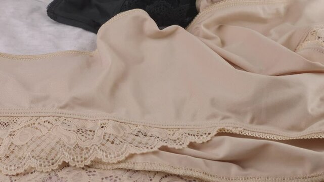 Knitted casual, women's underwear, black, gray and beige panties rotate on display case.