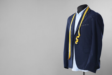 Semi-ready jacket, shirt and measuring tape on mannequin against gray background, space for text
