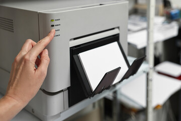 Woman using modern printer indoors, closeup. Printing house