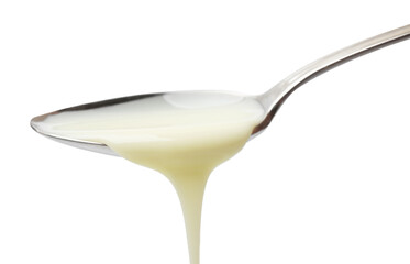 Delicious condensed milk pouring from spoon isolated on white