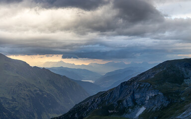 Fototapeta premium Dark storm clouds over the Hohe Tauern mountain range in Austria. Mystic mood with mountain layers and rays of sun.