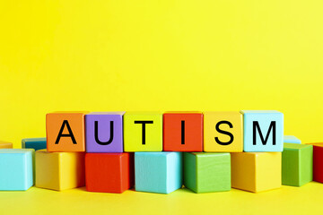 Word Autism made of colorful cubes on yellow background, space for text