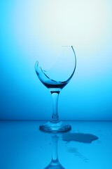 Broken glass with spilled wine against light blue gradient background