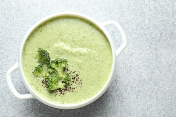 Delicious broccoli cream soup in bowl on light table, top view