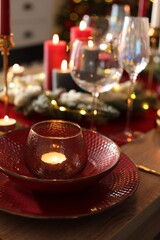 Christmas place setting with festive decor on wooden table in room, closeup