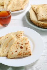 Tasty crepes on white wooden table, closeup