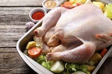 Raw turkey with different vegetables and spices on wooden table, closeup