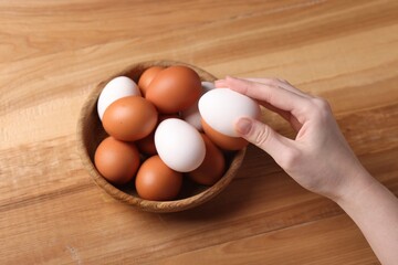 Woman with raw eggs at wooden table, closeup