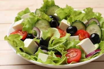 Delicious fresh Greek salad on light wooden table, closeup