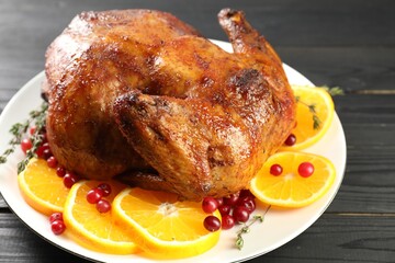 Delicious baked turkey, orange slices, cranberries and thyme on gray wooden table, closeup