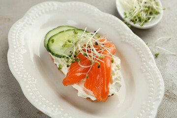 Delicious bruschetta with salmon, cream cheese and cucumber on light table, closeup