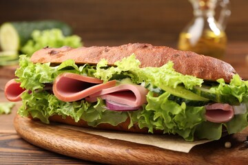 Delicious baguette sandwich with ham on wooden table, closeup