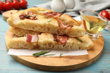 Pieces of delicious focaccia bread with bacon served on blue wooden table, closeup