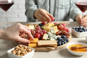 Women enjoying different snacks and wine during brunch at light grey table indoors, closeup