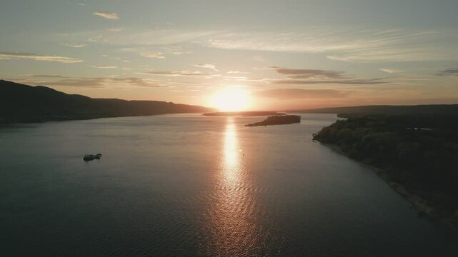 Tranquil sunset over river with cargo ship sailing