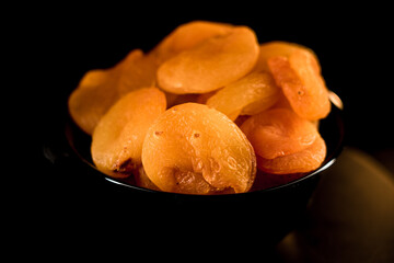 Dried apricots on a black plate showcasing intricate textures and vibrant colors, perfect for snacking or baking