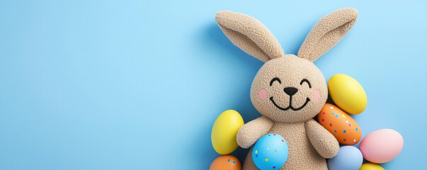 Obraz premium Cute bunny plush toy surrounded by colorful Easter eggs on blue background