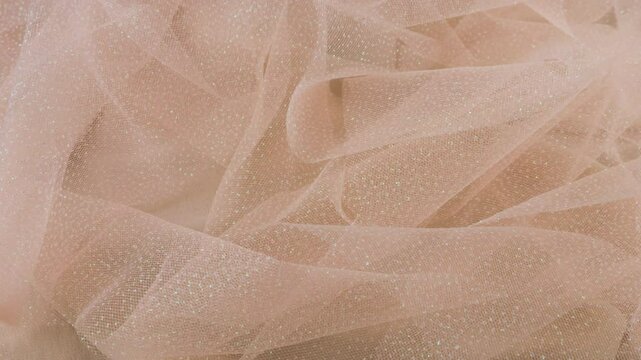 Pleats of delicate airy organza in pink tones rotate on the showcase. The theme of a wedding, bride, dress, fashion.