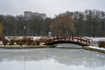 A wooden bridge by a frozen pond in Moscow on a gray winter day