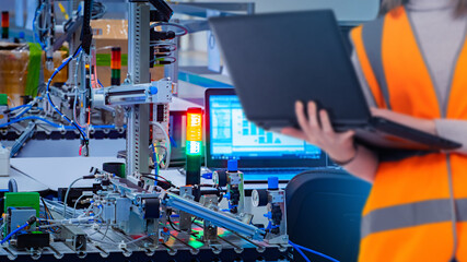 Industrial automation. Development of robots for factory. Science of mechatronics. Cropped woman with laptop near industrial robot. Lady develops industrial automation. Creating robot for production