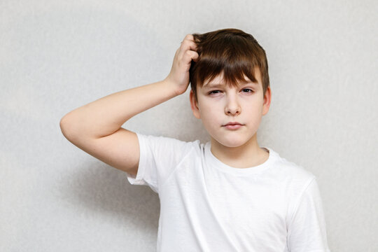 Ten year old boy scratching his head thoughtfully. Close-up portrait