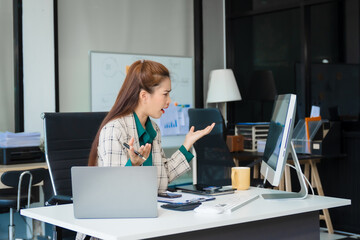Obraz premium Attractive Asian businesswoman in formal business attire is working at her desk with a laptop and mobile phone, focusing on corporate law, contracts, compliance, and law firm marketing strategies.