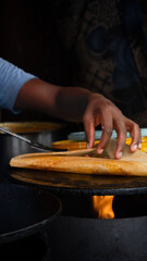 Man cooking Dosa Traditional South Indian breakfast. Concept of Indian cousin. Hand of Indian man clocking street food on the side of the road. Traditional Indian crepe. Concept Street food and travel