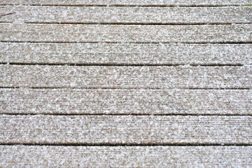 A Frost-Covered Wooden Walkway, Showcasing the Intricate Grain of the Wood and the Tranquil Beauty of a Winter Morning.