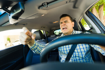 Angry hispanic man in car shouting and gesturing while on his way to work