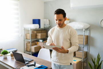 Latin business owner overseeing his online business with a digital tablet in hand at his warehouse