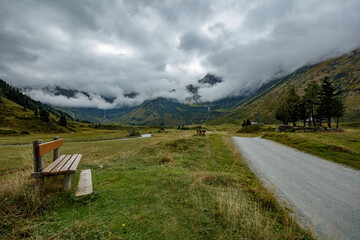 Cloudy view over Nassfelder Tal in Salzburg, Oostenrijk with a rustic bench by a winding path