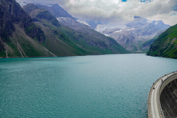 Kaprun high mountain reservoirs, Stausee Mooserboden coastline and Mooserbodenstrasse - cloudy summer day, August 20, 2024. Mountains, glacier, water reservoir, road - view before the storm from top.