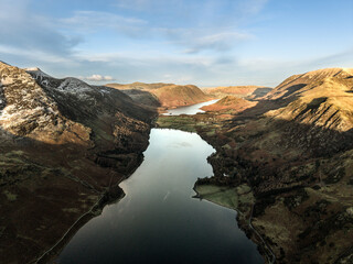 Dramatic aerial drone landscape in Autumn Winter of snowcapped mountains around Buttermere in Lake District at sunrise