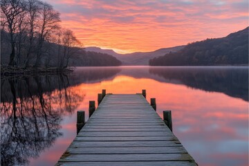 Fototapeta premium Wooden dock extending into tranquil lake at sunset