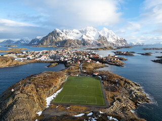 Aerial shot of a soccer field on an island with mountains in the background © DVS - Drone Visuals