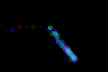 Christmas lights in bokeh. Outside in December. Red and fire green and blue colorful bokeh on a black background, bokeh abstract background. Orange Christmas background. Colorful Christmas bokeh 
