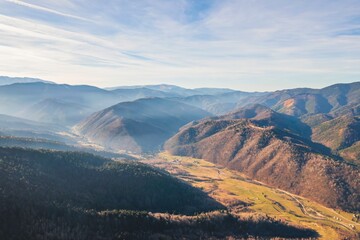 The breathtaking view captures rolling hills and tranquil valleys beneath a soft morning mist,...