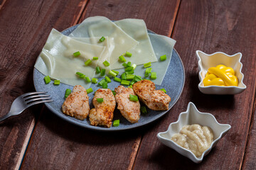 Thin khinkal with meat and herbs and various sauces in a plate on a wooden table