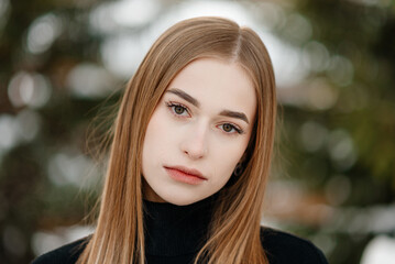 Naklejka premium young stunning serious beautiful blond caucasian woman in black sweater standing in pine forest in winter snowy day