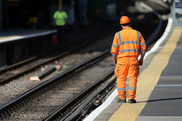 Fototapeta premium Railway worker inspects tracks on station platform