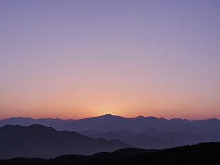 Obraz premium a serene and minimalistic sunset over a silhouette of distant mountains.