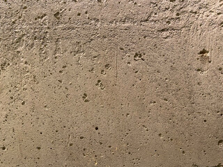 A concrete wall with scattered pores and subtle lighting highlights.