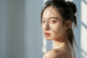 Naklejka premium Young Asian woman, profile view, long dark hair, sunlit face, natural beauty, soft lighting, serene expression, windswept hair, blue sky background, minimalist portrait, ethereal atmosphere, gentle br